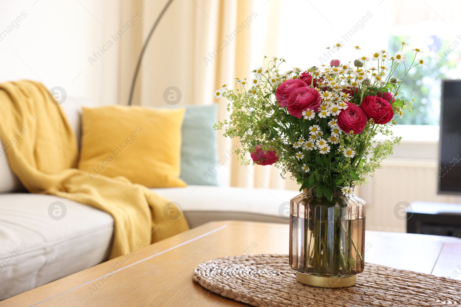 Photo of Beautiful ranunculus flowers and chamomiles in vase on table indoors