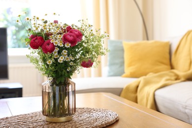 Photo of Beautiful ranunculus flowers and chamomiles in vase on table indoors