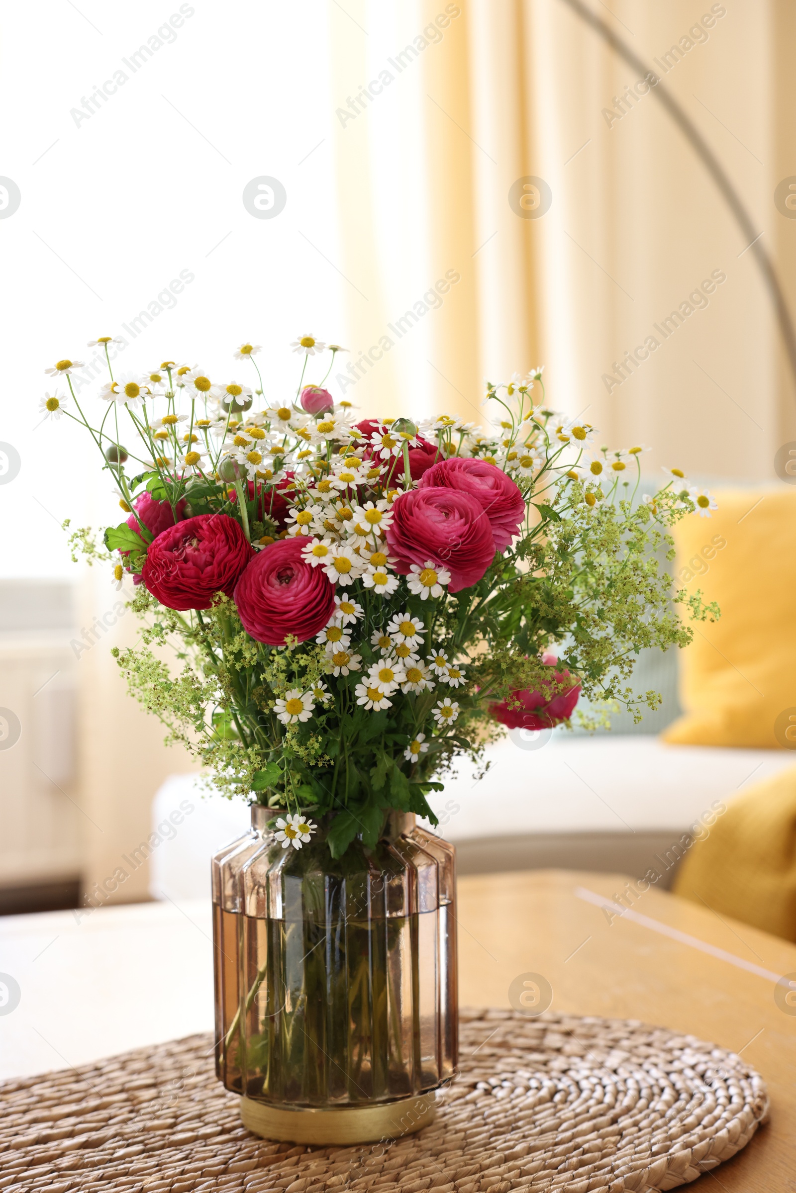 Photo of Beautiful ranunculus flowers and chamomiles in vase on table indoors