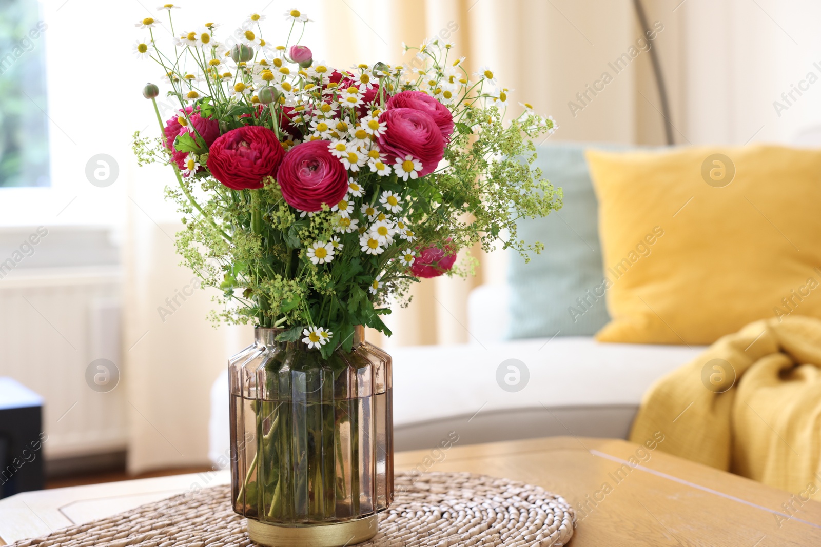 Photo of Beautiful ranunculus flowers and chamomiles in vase on table indoors