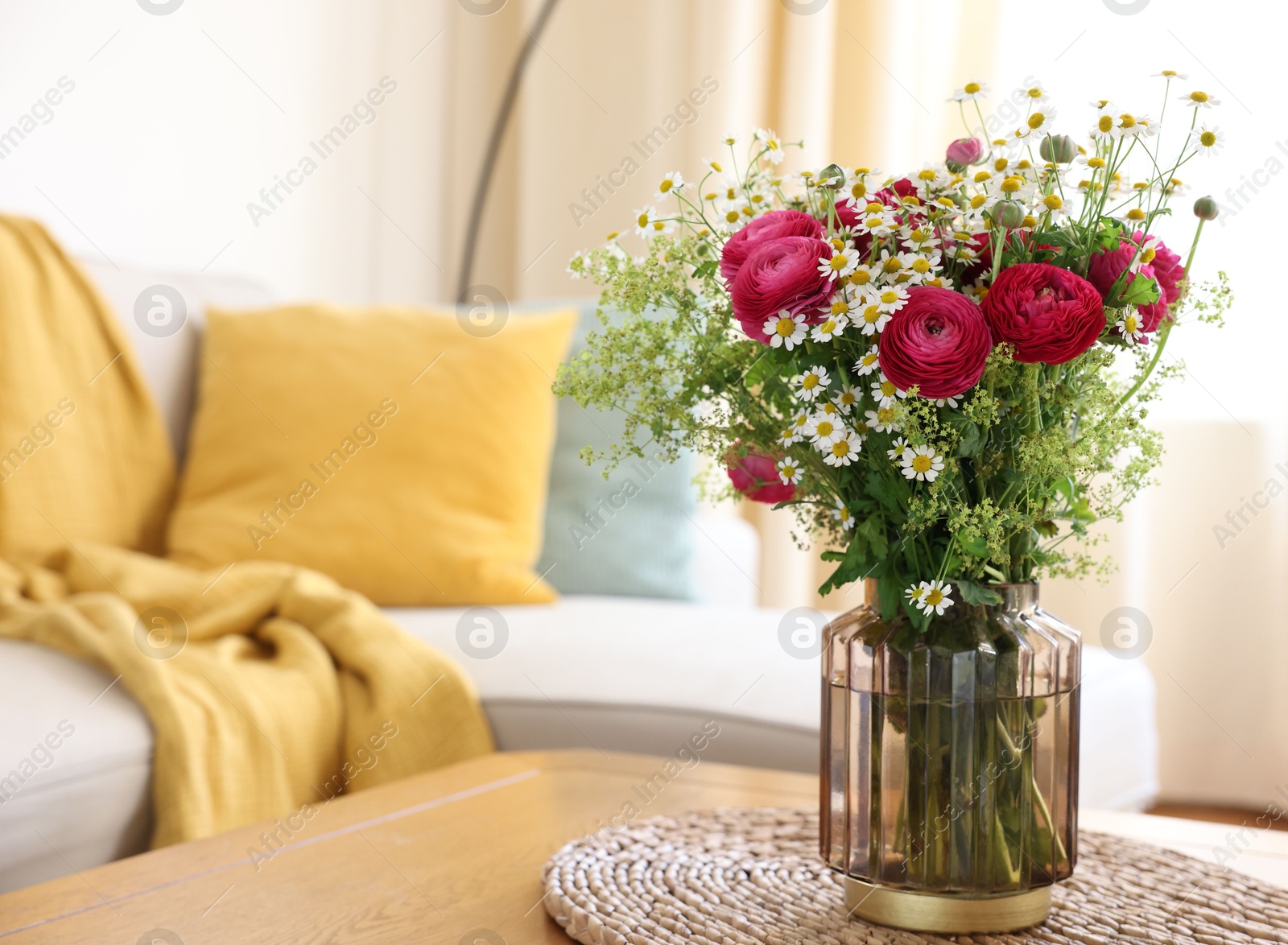 Photo of Beautiful ranunculus flowers and chamomiles in vase on table indoors