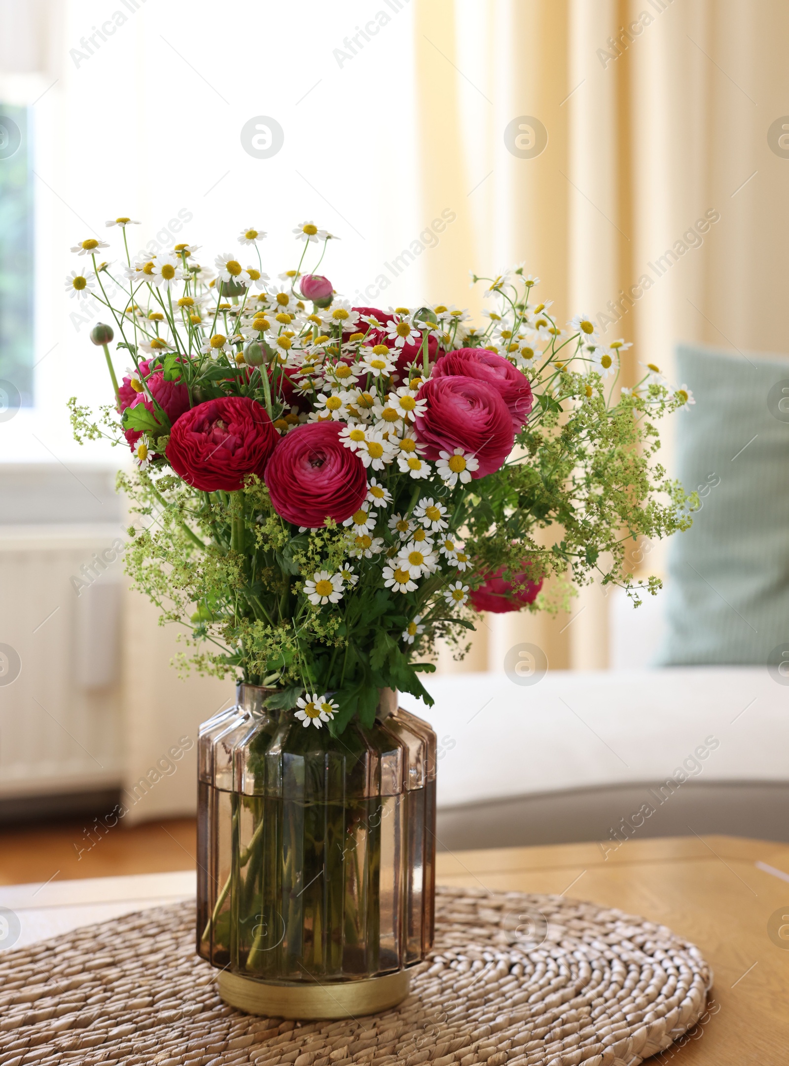 Photo of Beautiful ranunculus flowers and chamomiles in vase on table indoors