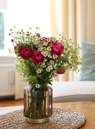 Photo of Beautiful ranunculus flowers and chamomiles in vase on table indoors