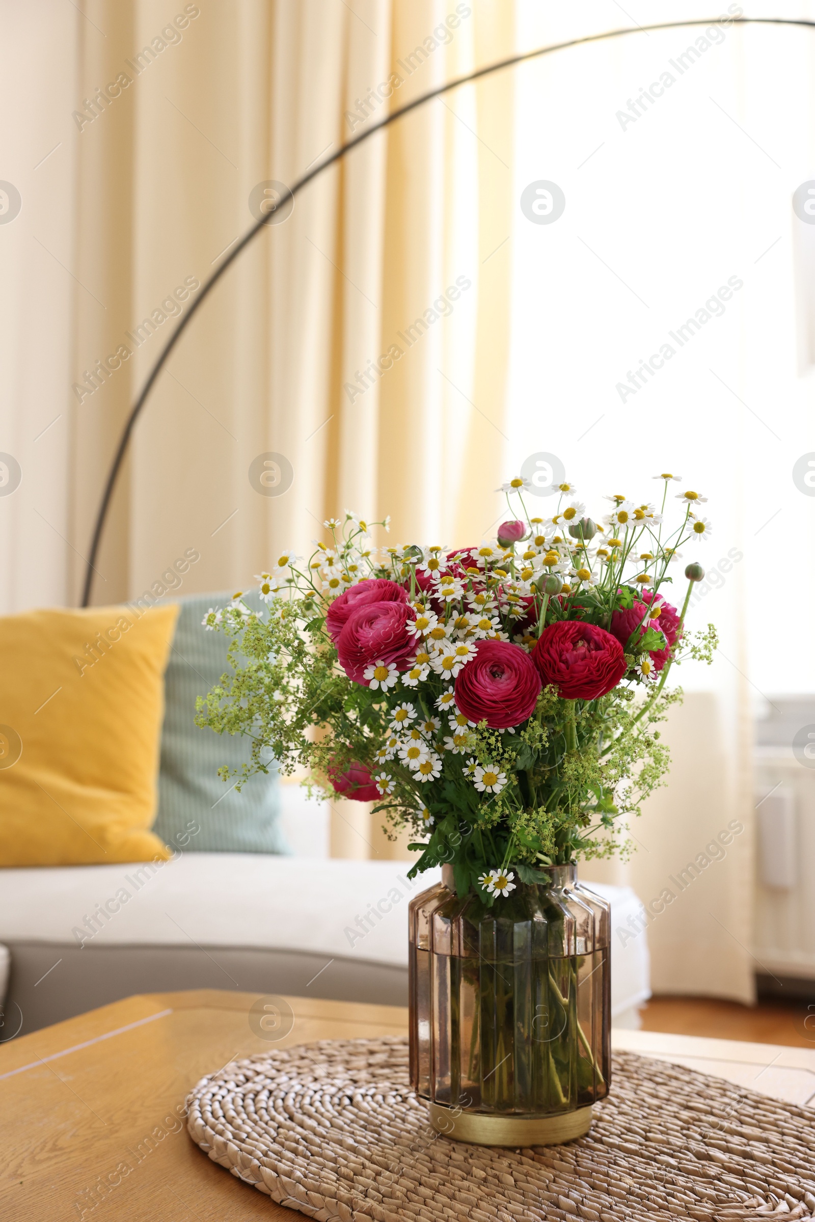 Photo of Beautiful ranunculus flowers and chamomiles in vase on table indoors