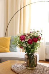 Photo of Beautiful ranunculus flowers and chamomiles in vase on table indoors