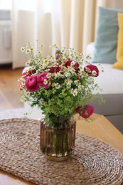 Photo of Beautiful ranunculus flowers and chamomiles in vase on table indoors