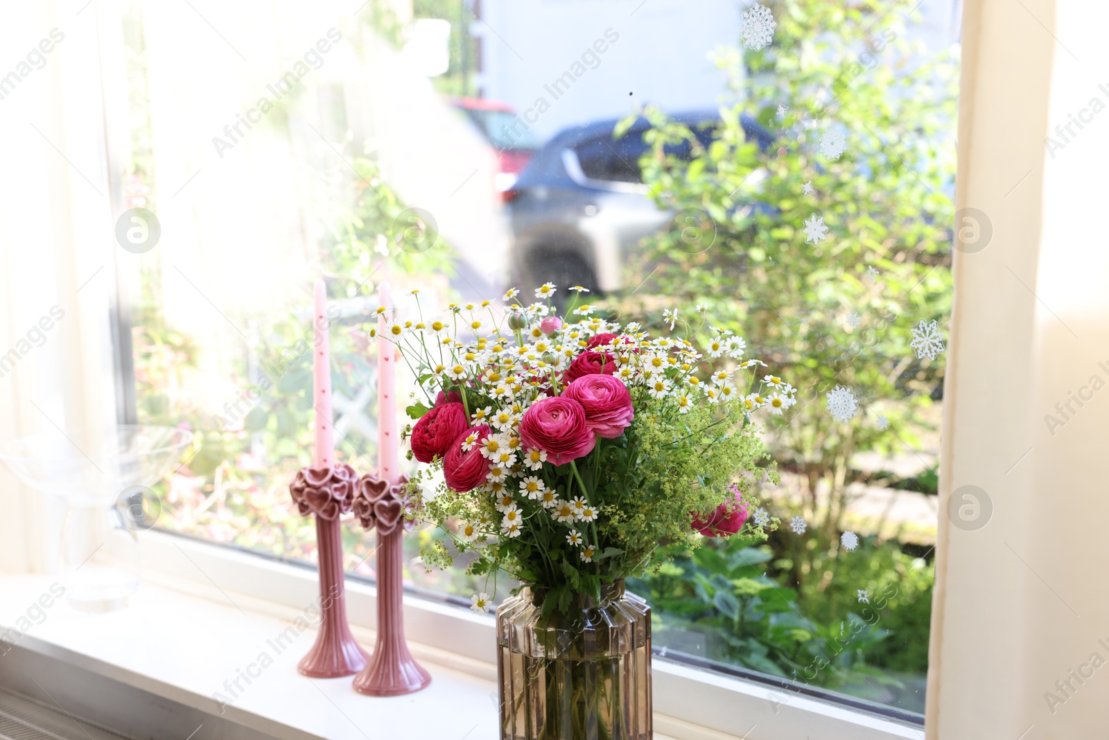 Photo of Beautiful ranunculus flowers and chamomiles in vase on windowsill indoors