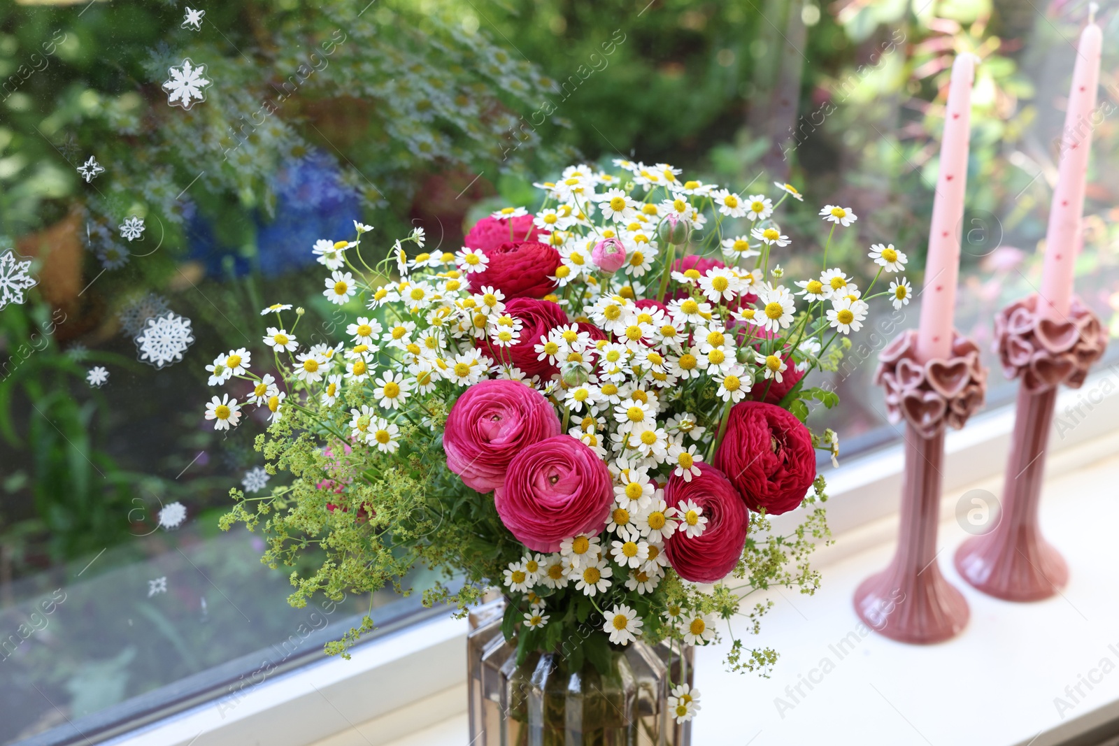 Photo of Beautiful ranunculus flowers and chamomiles in vase on windowsill indoors