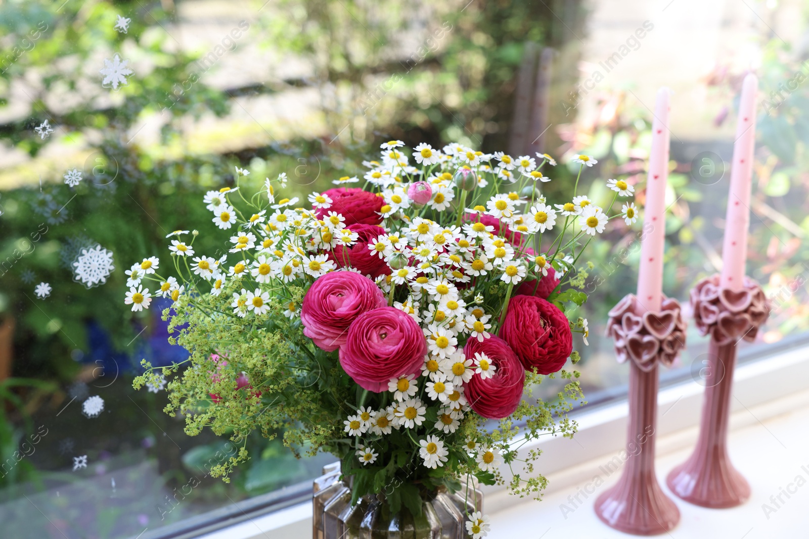 Photo of Beautiful ranunculus flowers and chamomiles in vase on windowsill indoors