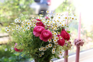 Photo of Beautiful ranunculus flowers and chamomiles near window indoors