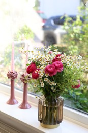 Photo of Beautiful ranunculus flowers and chamomiles in vase on windowsill indoors