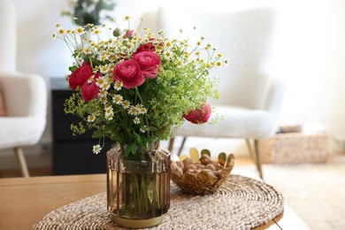 Photo of Beautiful ranunculus flowers and chamomiles in vase on table indoors