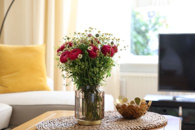 Beautiful ranunculus flowers and chamomiles in vase on table indoors