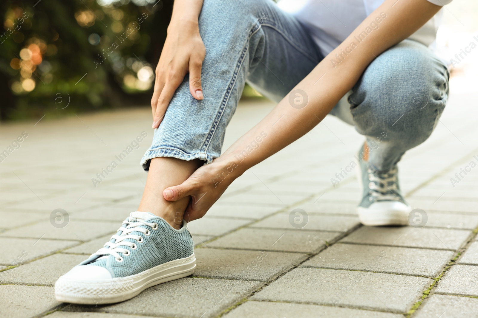 Photo of Woman suffering from foot pain outdoors, closeup