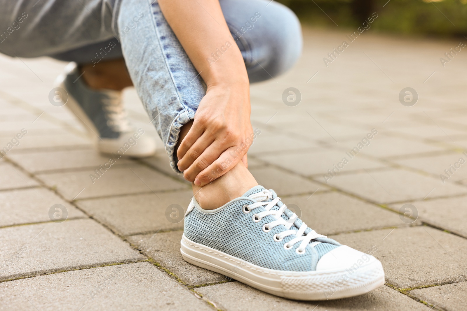 Photo of Woman suffering from foot pain outdoors, closeup