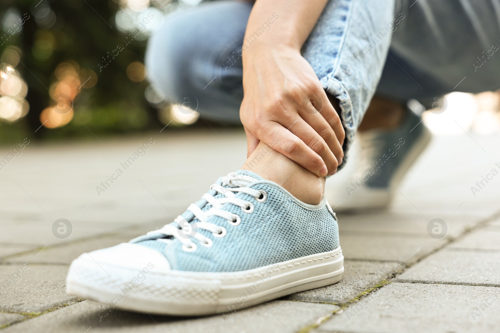 Photo of Woman suffering from foot pain outdoors, closeup