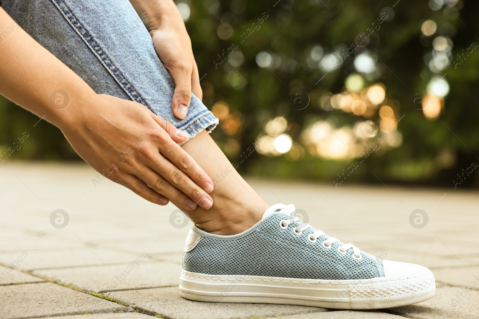 Photo of Woman suffering from foot pain outdoors, closeup