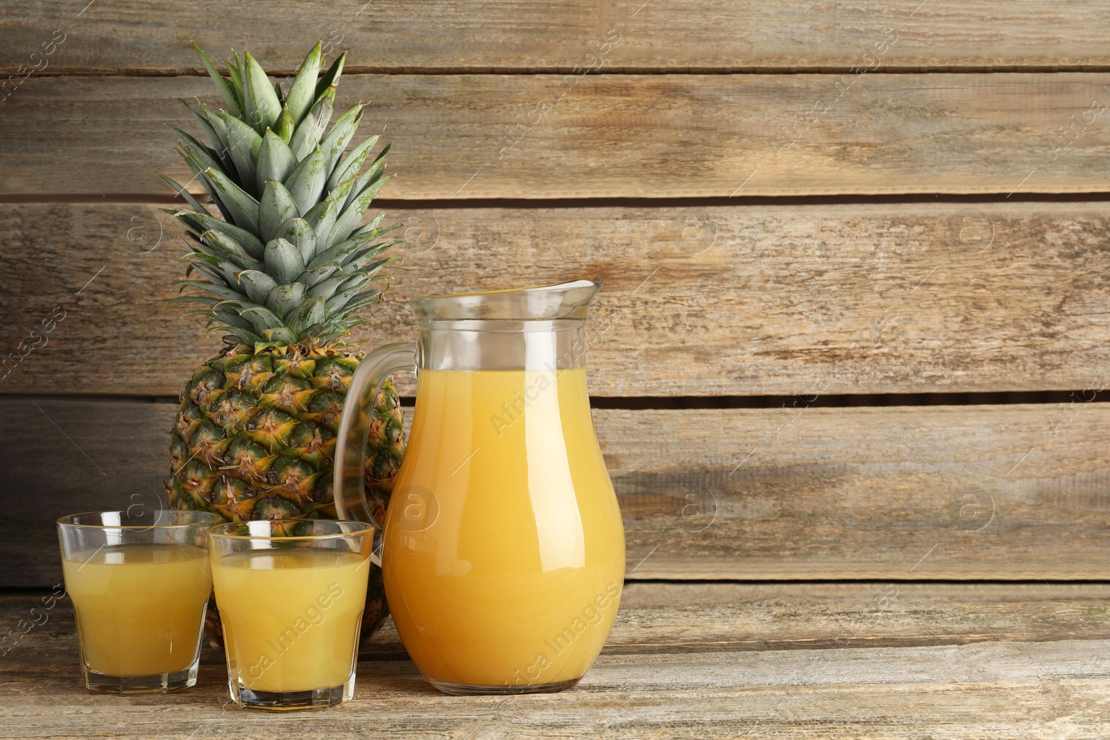 Photo of Tasty pineapple juice and fresh fruit on wooden table. Space for text