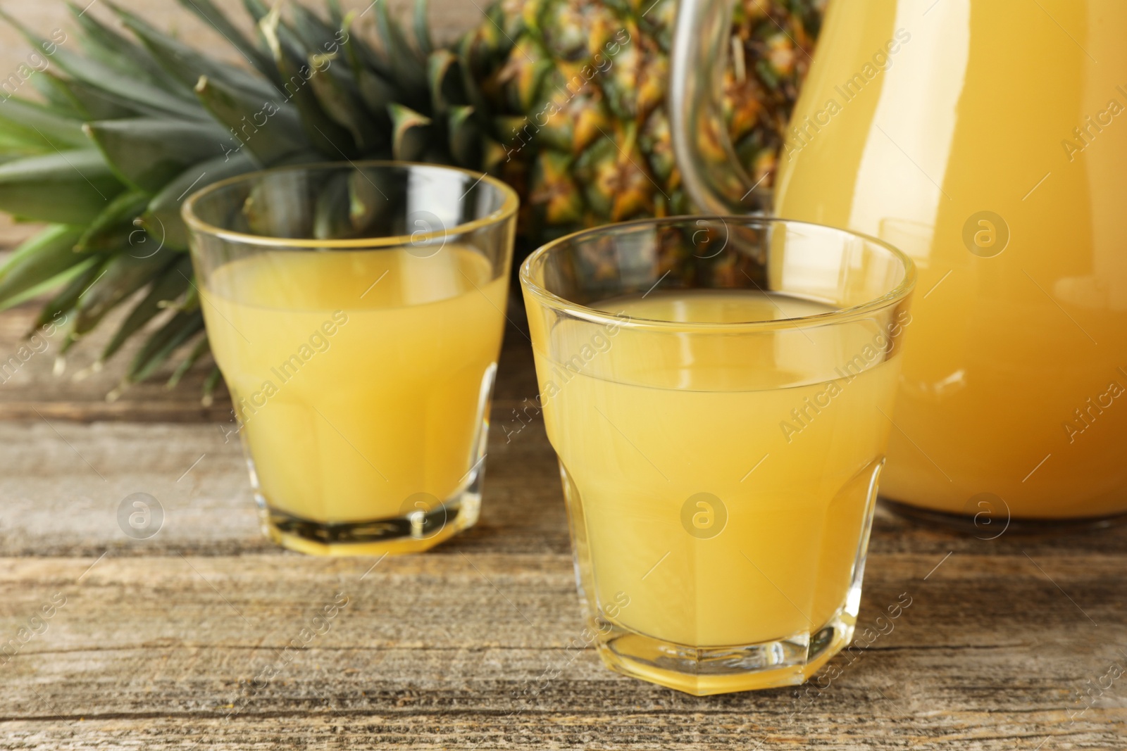 Photo of Tasty pineapple juice and fresh fruit on wooden table, closeup