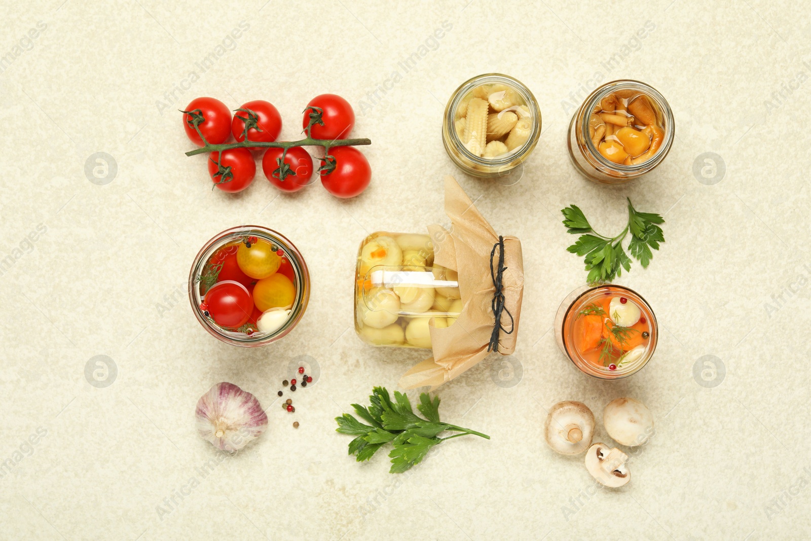 Photo of Different pickled products in jars and fresh ingredients on beige textured table, flat lay