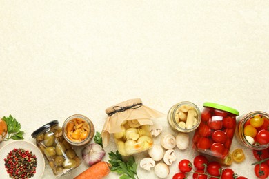 Photo of Different pickled products in jars and fresh ingredients on beige textured table, flat lay. Space for text