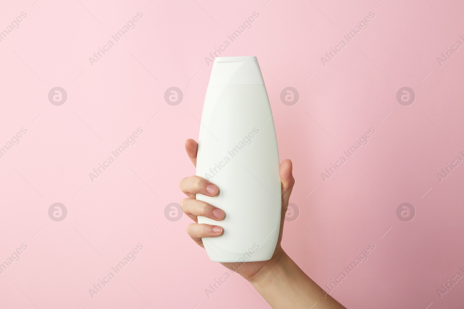 Photo of Woman with shampoo bottle on pink background, closeup