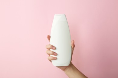 Photo of Woman with shampoo bottle on pink background, closeup