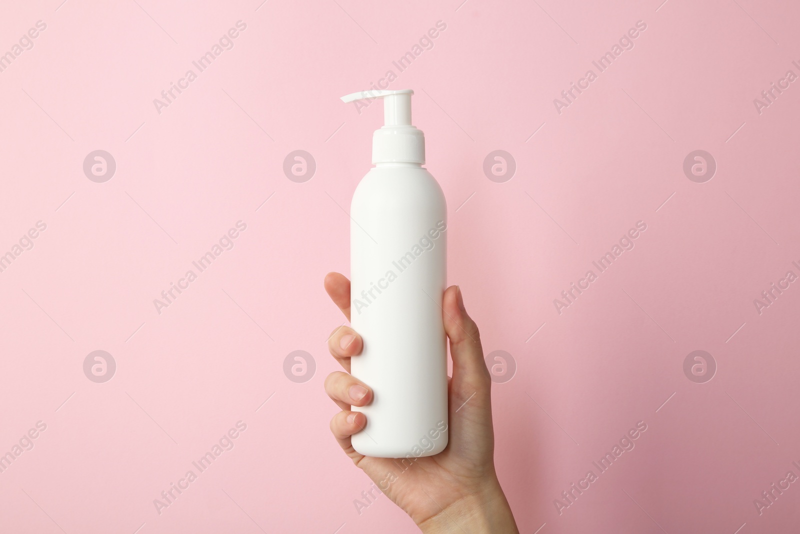 Photo of Woman with shampoo bottle on pink background, closeup