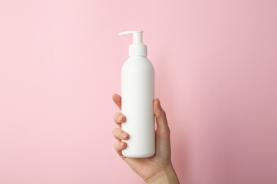 Photo of Woman with shampoo bottle on pink background, closeup