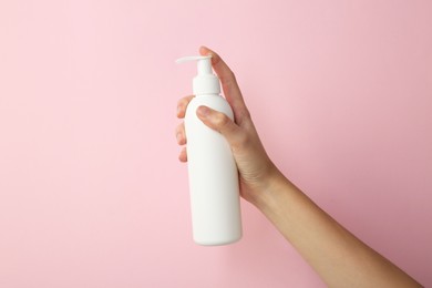 Photo of Woman with shampoo bottle on pink background, closeup