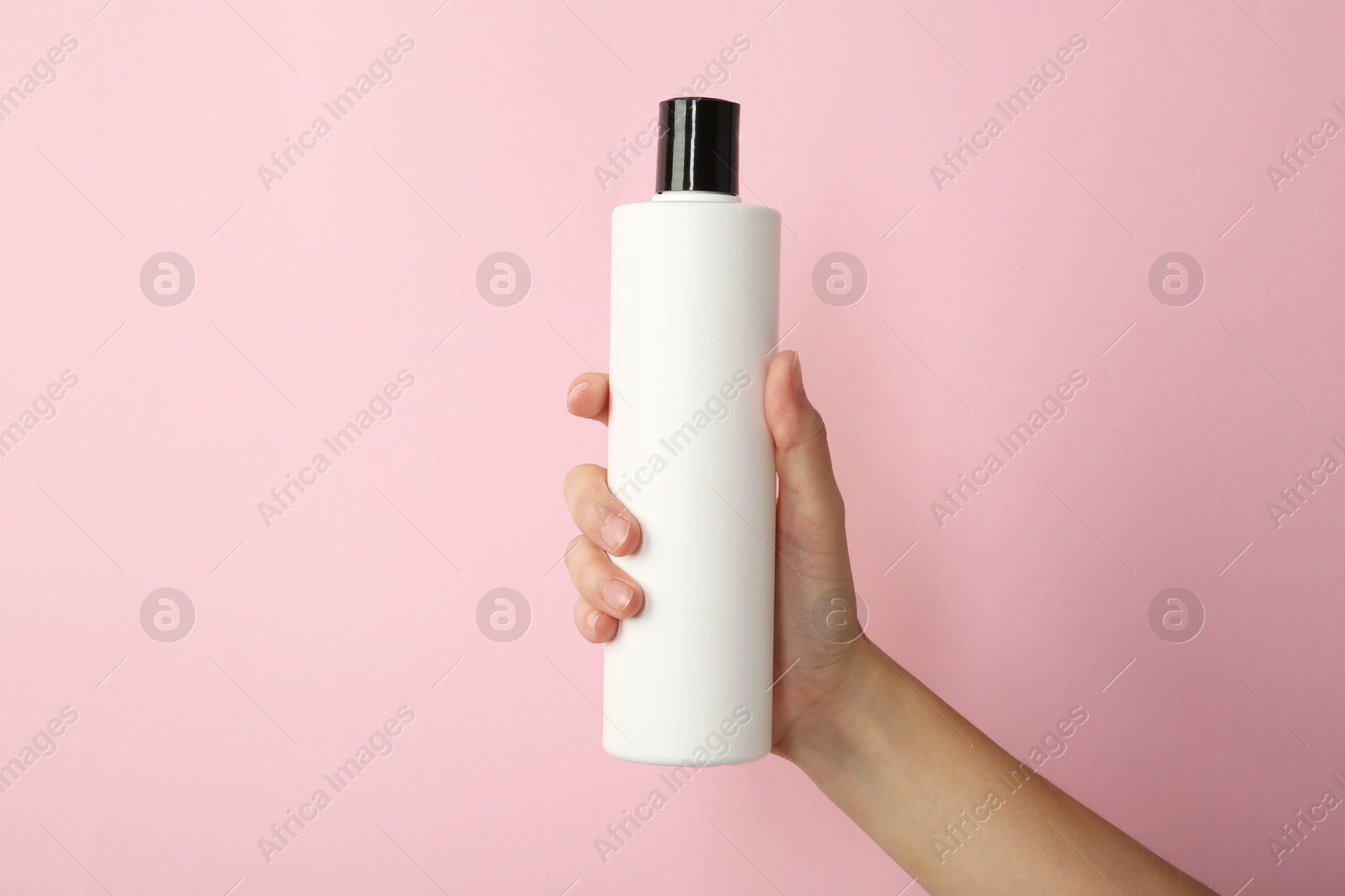 Photo of Woman with shampoo bottle on pink background, closeup