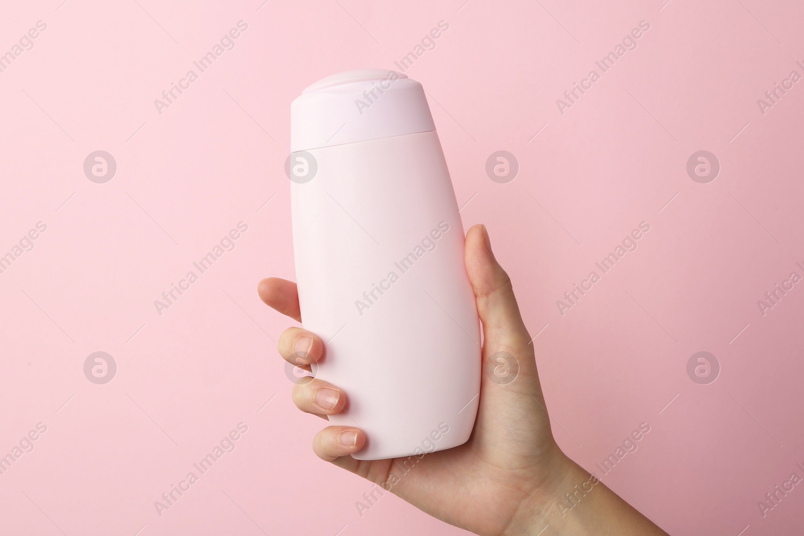 Photo of Woman with shampoo bottle on pink background, closeup