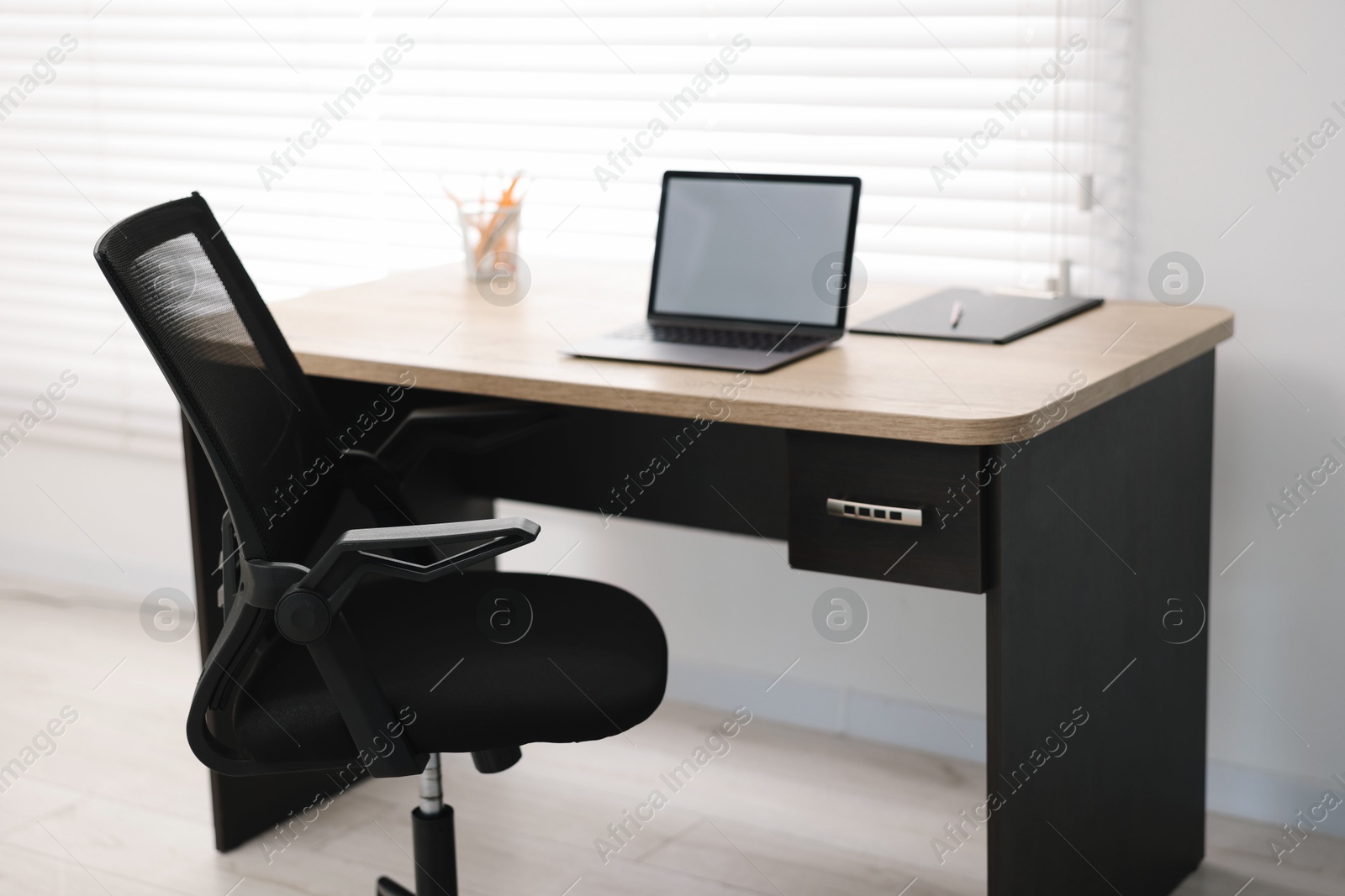 Photo of Black chair, laptop and desk in office