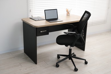 Photo of Black chair, laptop and desk in office