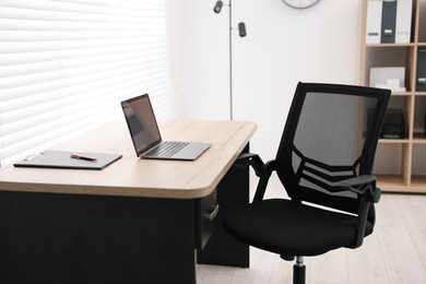 Photo of Black chair, laptop and desk in office