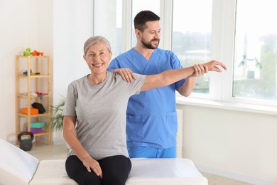 Photo of Physiotherapist working with senior patient in rehabilitation center