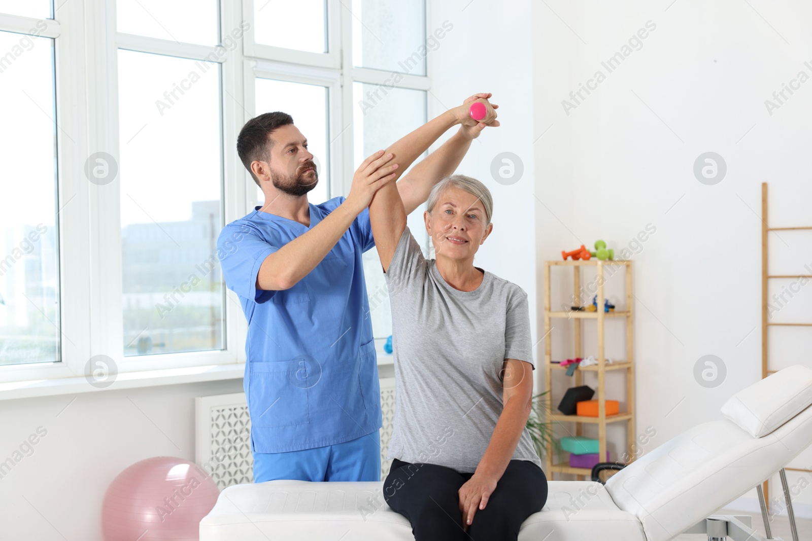 Photo of Senior patient exercising under physiotherapist supervision in rehabilitation center