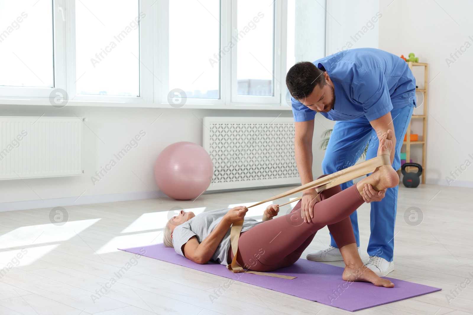 Photo of Physiotherapist working with senior patient in rehabilitation center