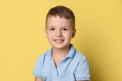 Portrait of cute little boy on yellow background