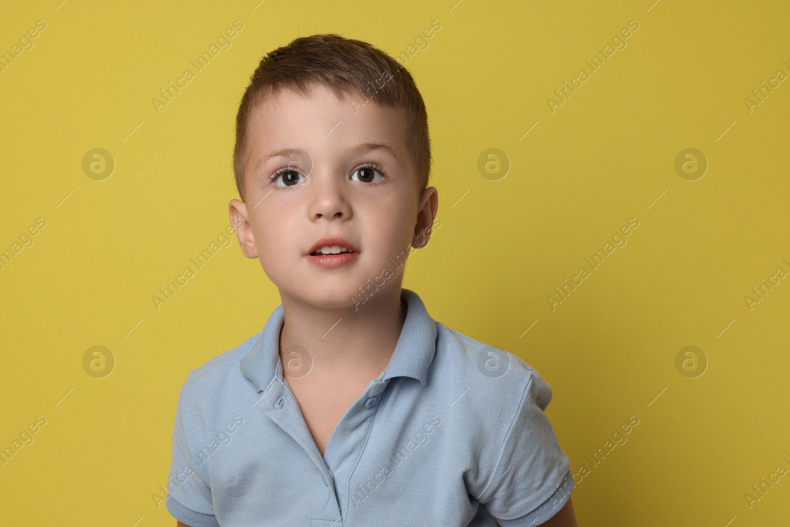 Photo of Portrait of cute little boy on yellow background