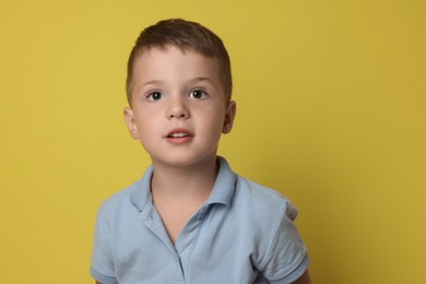 Photo of Portrait of cute little boy on yellow background