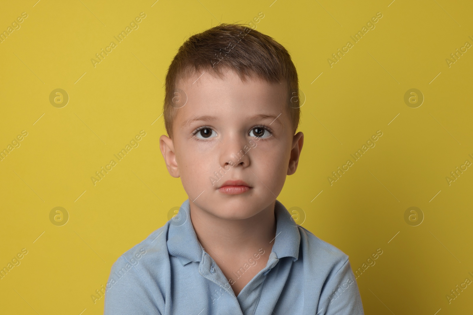 Photo of Portrait of cute little boy on yellow background