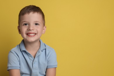 Portrait of cute little boy on yellow background, space for text