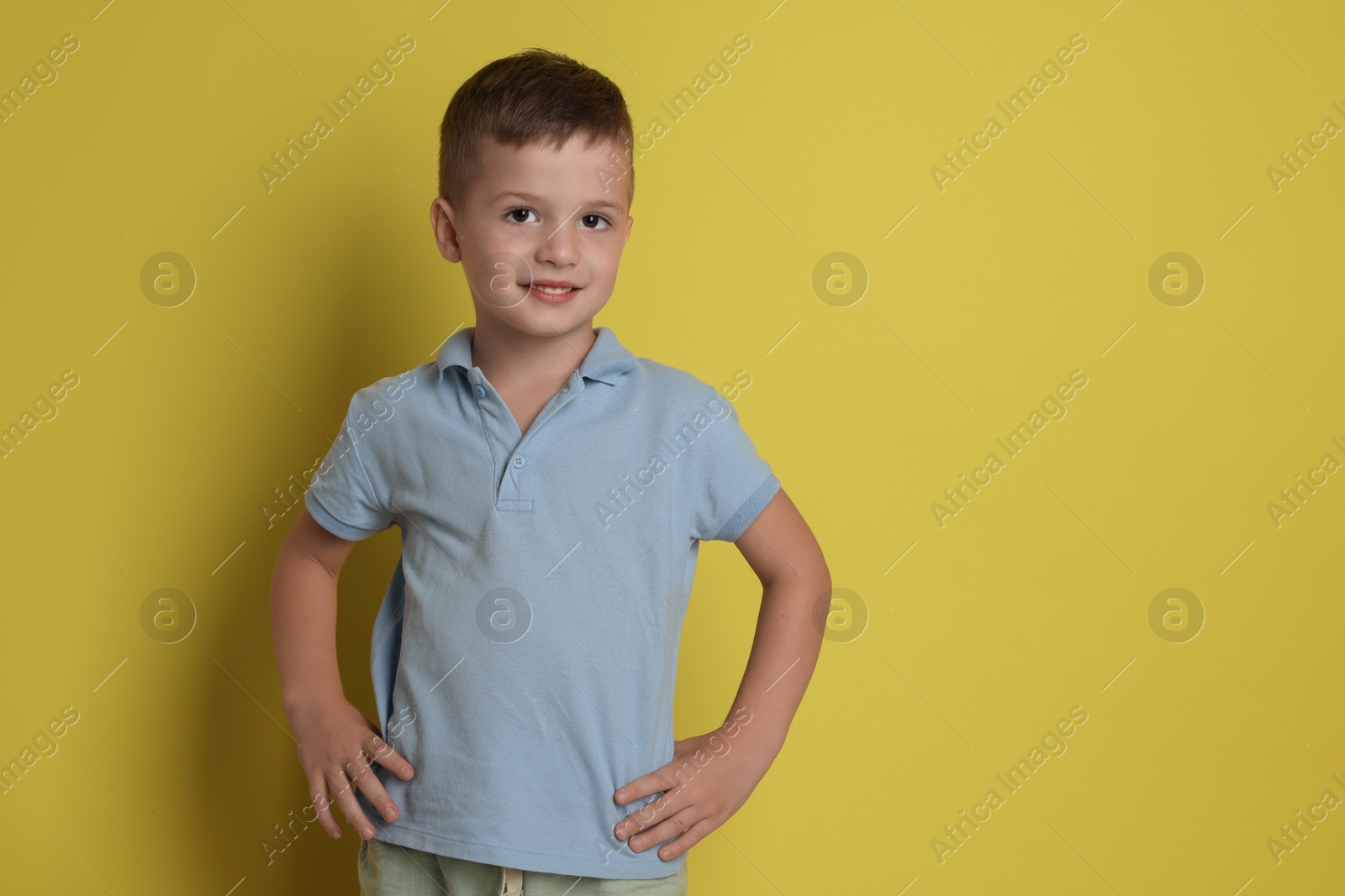 Photo of Portrait of cute little boy on yellow background, space for text