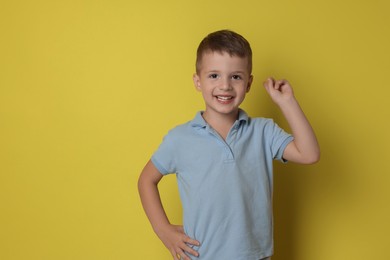 Photo of Portrait of cute little boy on yellow background, space for text