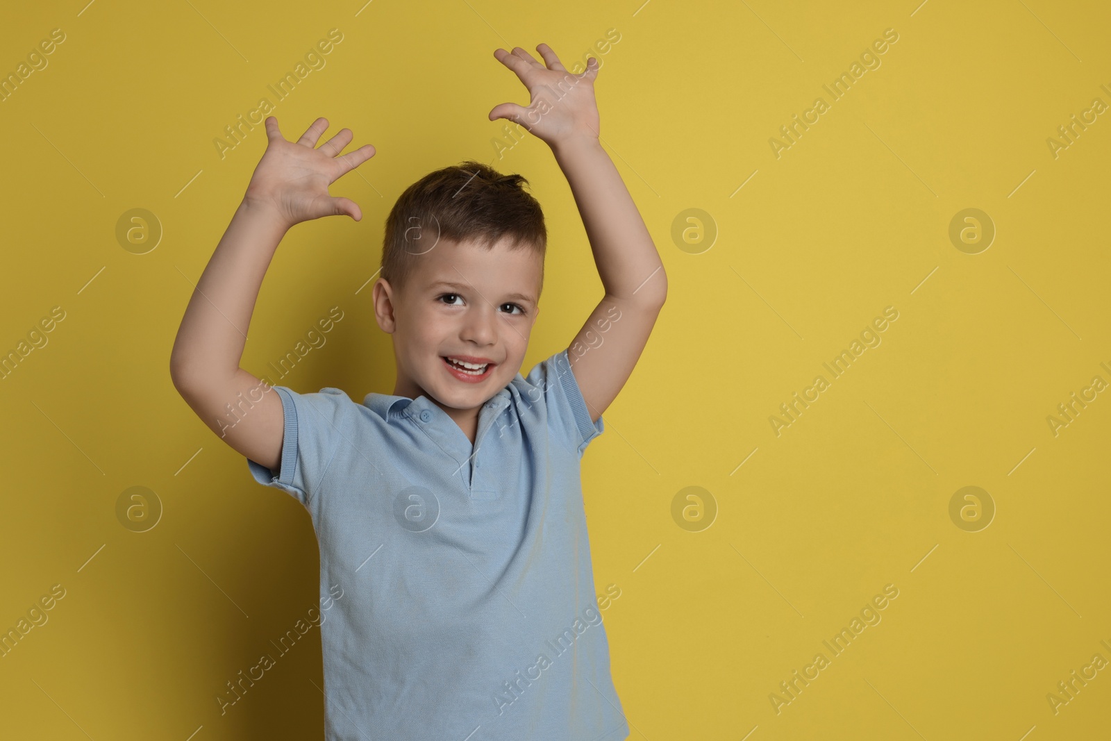 Photo of Portrait of cute little boy on yellow background, space for text