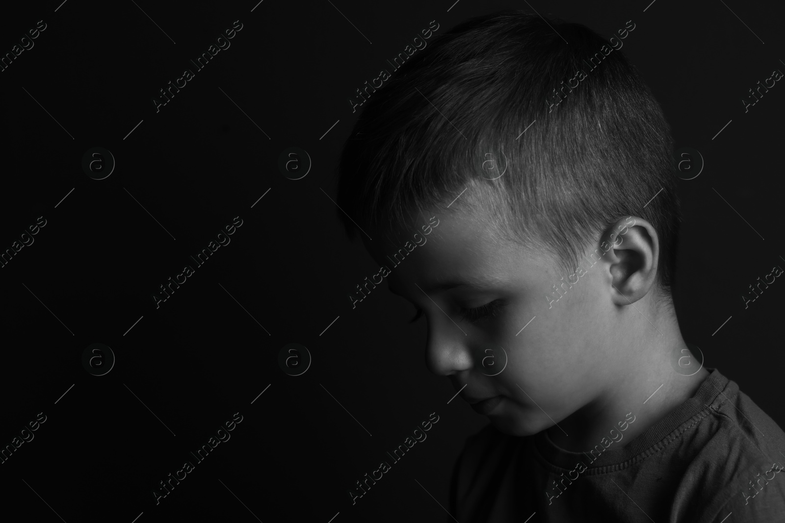 Photo of Portrait of sad little boy on dark background, space for text. Black and white effect