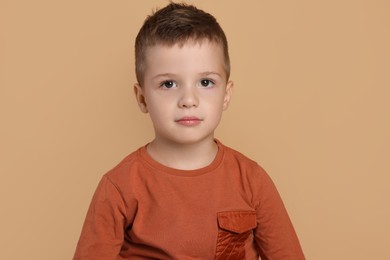 Portrait of cute little boy on pale background