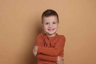 Portrait of cute little boy on pale background