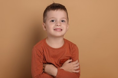 Portrait of cute little boy on pale background